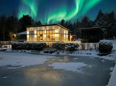a house with the aurora in the sky at Spa & Comfort - Chalet KG Petit lac Lambton in Lambton