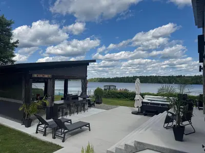 a patio with chairs and a gazebo and a lake at Spa & Comfort - Chalet KG Petit lac Lambton in Lambton