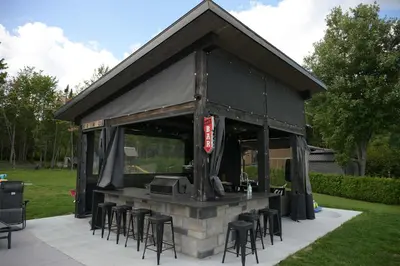 a building with a bar with stools around it at Spa & Comfort - Chalet KG Petit lac Lambton in Lambton