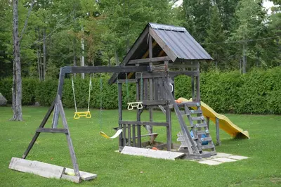 a small playground with a slide and a swing at Spa & Comfort - Chalet KG Petit lac Lambton in Lambton