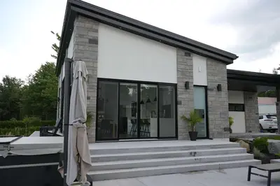 a house with glass windows and an umbrella at Spa & Comfort - Chalet KG Petit lac Lambton in Lambton