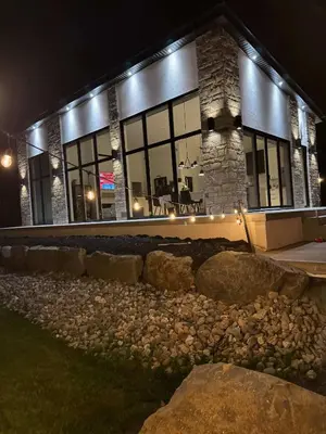 a building at night with rocks in front of it at Spa & Comfort - Chalet KG Petit lac Lambton in Lambton