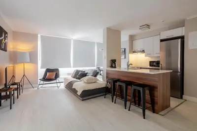 a living room with a couch and a kitchen at Modern 1BR Downtown Suite - High-Speed Wi-Fi in Montréal