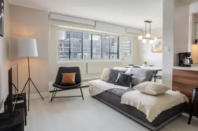 a bedroom with a bed and a chair and windows at Modern 1BR Downtown Suite - High-Speed Wi-Fi in Montréal