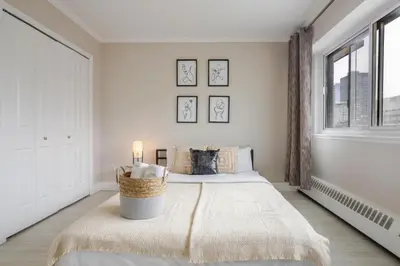 a white bedroom with a bed and a window at Modern 1BR Downtown Suite - High-Speed Wi-Fi in Montréal