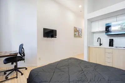 a bedroom with a bed and a desk and a tv at Studio pour deux-location hebdomadaire avec parking gratuit in Montréal