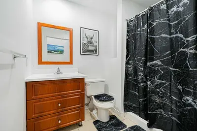 a bathroom with a black shower curtain and a toilet at Studio pour deux-location hebdomadaire avec parking gratuit in Montréal