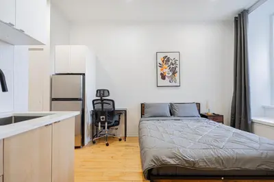 a small bedroom with a bed and a kitchen at Studio 2 voyageurs-séjour hebdomadaire-Parking gratuit in Montréal