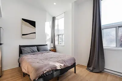a bedroom with a bed and two windows at Studio style pour 2- Location par Semaine-Parking gratuit in Montréal