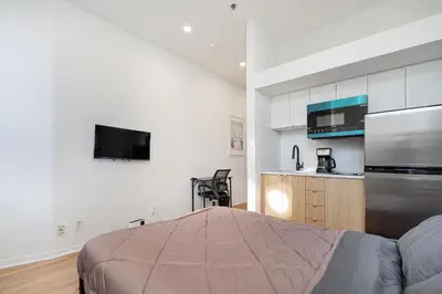 a bedroom with a bed and a kitchen with a refrigerator at Studio style pour 2- Location par Semaine-Parking gratuit in Montréal