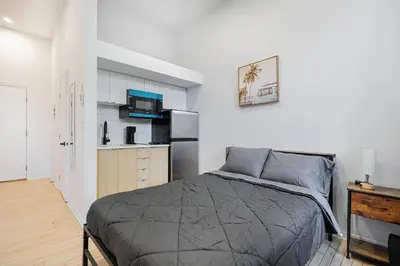 a bedroom with a bed and a kitchen with a refrigerator at Chic Studio pour 2- 7 jours- Parking gratuit in Montréal