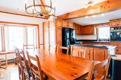 a kitchen with a wooden table and a kitchen with a stove at Le Repere du Lac - Lake View Access & Spa in Venise-en-Québec