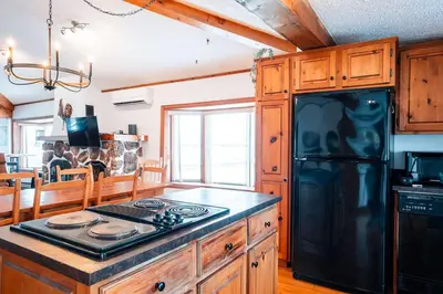 a kitchen with a black refrigerator and a stove at Le Repere du Lac - Lake View Access & Spa in Venise-en-Québec