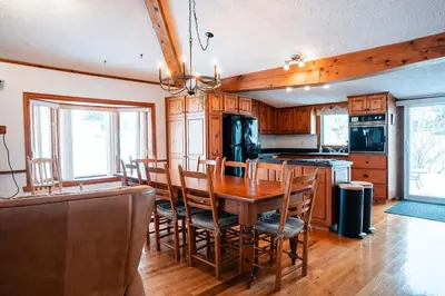 a kitchen with a wooden dining table and chairs at Le Repere du Lac - Lake View Access & Spa in Venise-en-Québec