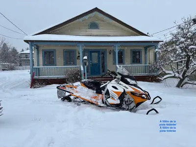a snow covered motorcycle parked in front of a house at Le Repere du Lac - Lake View Access & Spa in Venise-en-Québec