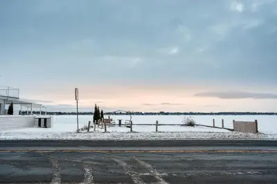 an empty road with snow on the side of a lake at Le Repere du Lac - Lake View Access & Spa in Venise-en-Québec