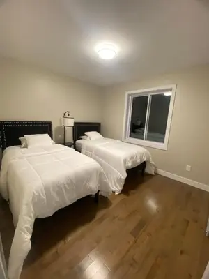 a bedroom with two beds with white sheets and a window at Spacious 4 Bedroom Family Retreat, Minutes from Montréal in Longueuil