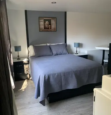 a bedroom with a bed with a blue blanket and two lamps at Bethel in Sherbrooke