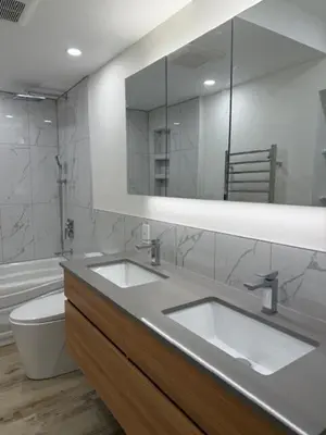 a bathroom with two sinks and a toilet and a mirror at Apartment with 3 bedrooms for long stays in Montréal