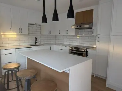 a kitchen with a white counter and stools in it at Apartment with 3 bedrooms for long stays in Montréal