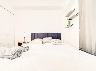 a white bedroom with a large white bed with two pillows at Vivez la ville depuis le centre in Montréal