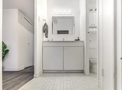 a white bathroom with a sink and a mirror at Vivez la ville depuis le centre in Montréal