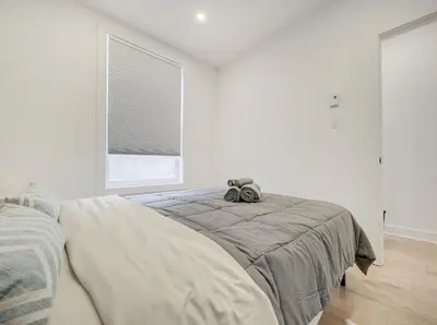 a white bedroom with a bed and a window at Confort moderne au cœur de Montréal in Montréal