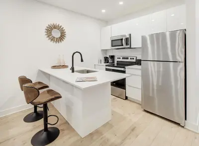 a white kitchen with a sink and a refrigerator at Confort moderne au cœur de Montréal in Montréal