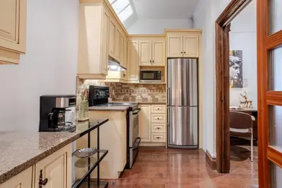 a kitchen with wooden cabinets and a stainless steel refrigerator at Bright Montreal Loft, Trendy Downtown Escape in Montréal