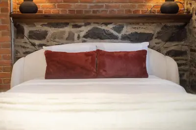 a white bed with two red pillows on it at Downtown Montreal Gem, Walk Everywhere Easily in Montréal