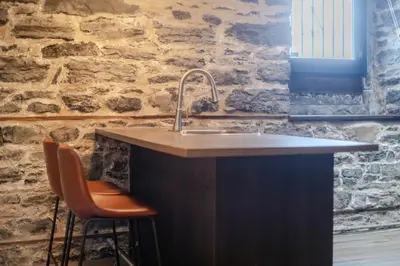 a kitchen counter with a sink and two chairs at Downtown Montreal Gem, Walk Everywhere Easily in Montréal