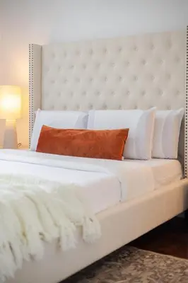 a white bed with an orange pillow on it at Urban Haven, Modern Comfort in Downtown MTL in Montréal