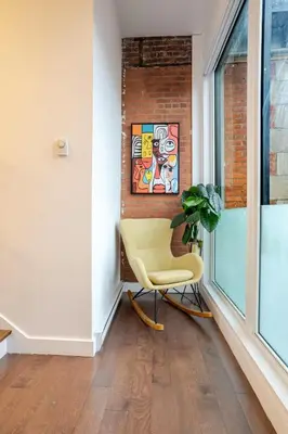 a yellow chair in a room with a brick wall at Urban Haven, Modern Comfort in Downtown MTL in Montréal