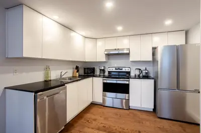 a kitchen with white cabinets and stainless steel appliances at Urban Haven, Modern Comfort in Downtown MTL in Montréal