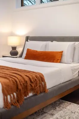 a large bed with an orange blanket on it at Stylish Retreat Near Crescent & Sainte-Catherine in Montréal