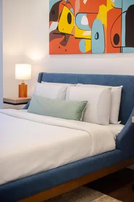 a bedroom with a blue bed with a painting on the wall at Stylish Retreat Near Crescent & Sainte-Catherine in Montréal