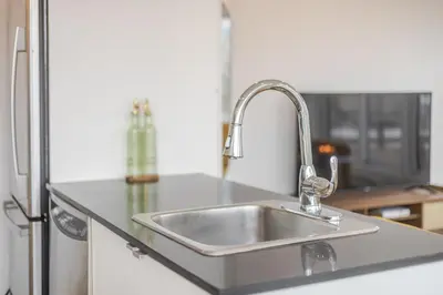 a stainless steel kitchen sink in front of a refrigerator at Montreal Downtown Haven, Walk to All Attractions in Montréal