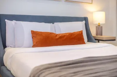 a large bed with white sheets and orange pillows at Chic City Hideaway, Vibrant Heart of Montreal in Montréal