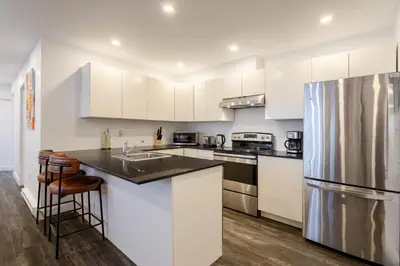 a kitchen with white cabinets and a stainless steel refrigerator at Chic City Hideaway, Vibrant Heart of Montreal in Montréal