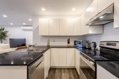 a kitchen with white cabinets and black counter tops at Chic City Hideaway, Vibrant Heart of Montreal in Montréal