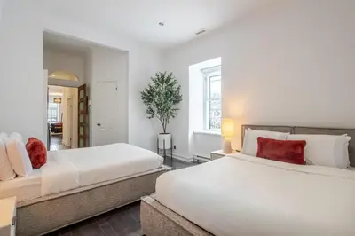 two beds in a bedroom with white walls and red pillows at Elegant Downtown Stay, Near Bell Centre MTL in Montréal