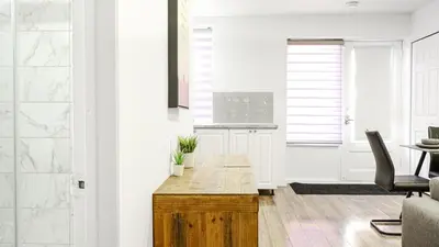 a white kitchen with a wooden table in a room at Appartement charmant proche des attractions in Montréal