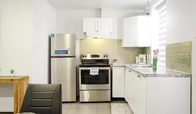 a kitchen with white cabinets and a stainless steel refrigerator at Appartement charmant proche des attractions in Montréal
