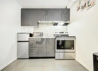 a kitchen with stainless steel appliances and gray cabinets at Appartement central à Montréal - À deux pas de tout in Montréal
