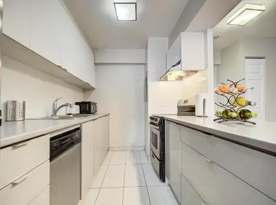 a white kitchen with a sink and a dishwasher at Appartement au centre-ville in Montréal