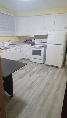 a kitchen with white appliances and a wooden floor at Résidence J'aime in Laval