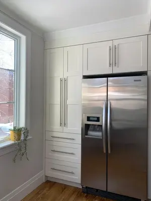 a kitchen with white cabinets and a stainless steel refrigerator at Appartements Saint-Alexandre in Longueuil