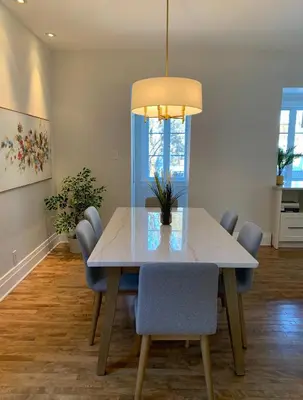 a dining room table with chairs and a light fixture at Appartements Saint-Alexandre in Longueuil