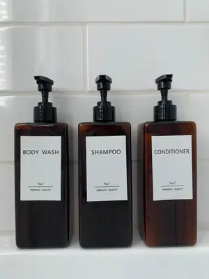 three bottles of soap and shampoo on a shelf at Appartements Saint-Alexandre in Longueuil