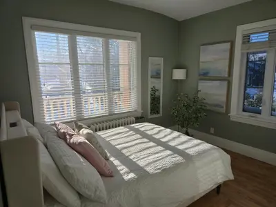 a bedroom with a large bed and two windows at Appartements Saint-Alexandre in Longueuil
